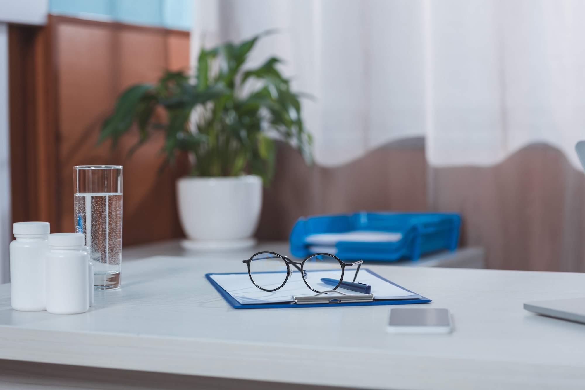 A healthcare administrative desk displaying eyeglasses resting on medical compliance and registration documents.